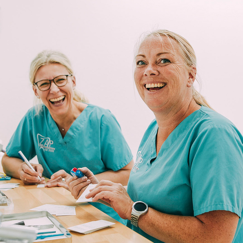 Frau Dr. Tilpe und eine Mitarbeiterin lachen gemeinsam in der Zahnarztpraxis am Park