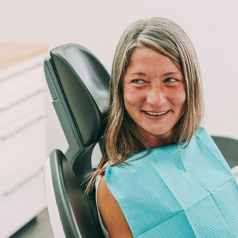 Eine Dame lächelt in die Kamera bevor ihr Veneers eingesetzt werden in der Zahnarztpraxis am Park